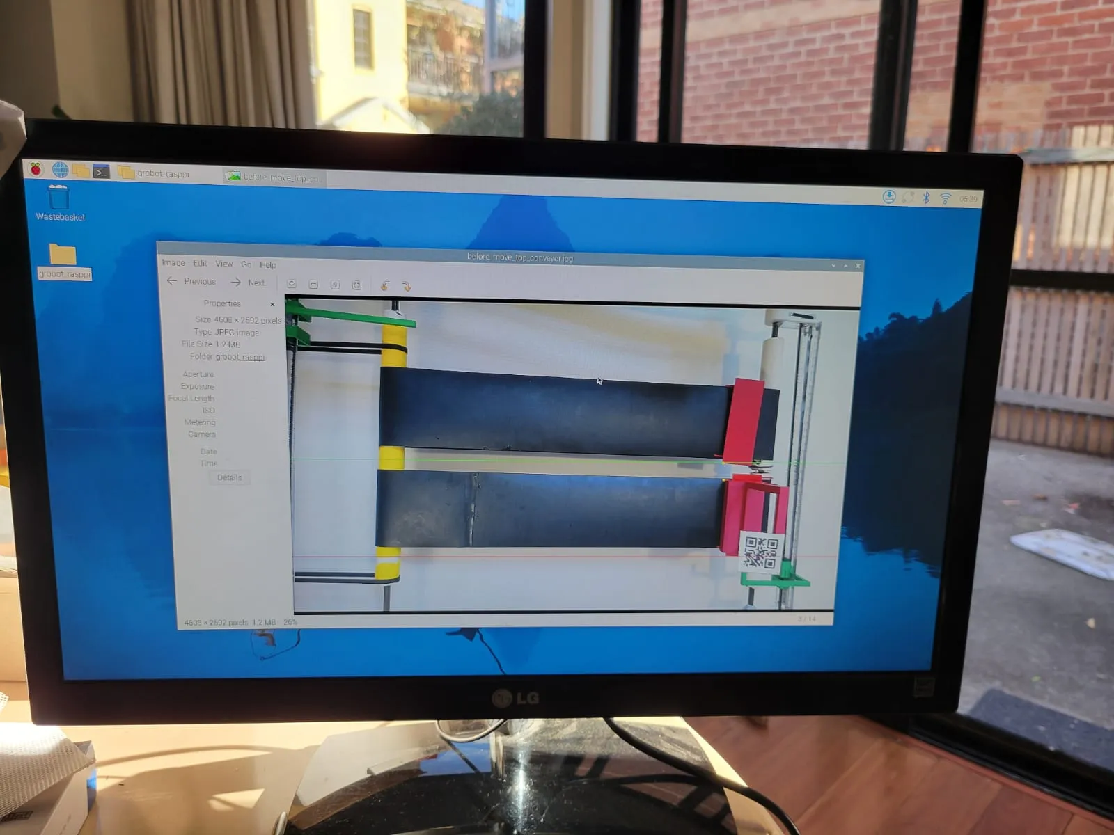 A monitor showing a captured photo of the conveyor system, filename before_move_top_conveyor.jpg, open on the Raspberry Pi desktop.